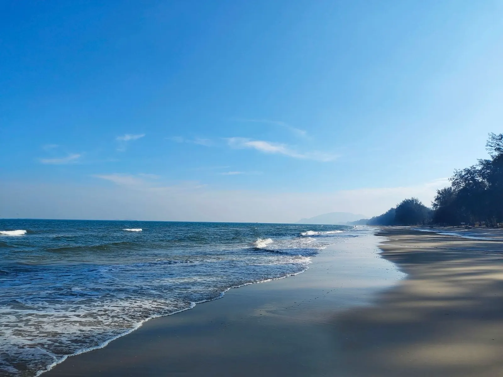 Waves on a quiet Hua Hin beach under a clear blue sky